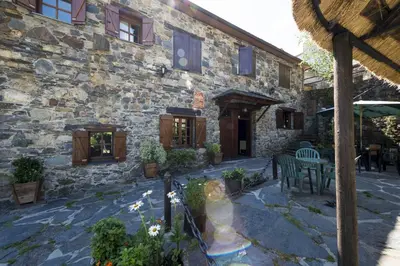 a stone building with a table and chairs in front of it at Hotel Rural Valle de Ancares in Pereda de Ancares
