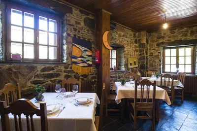 a dining room with tables and chairs and windows at Hotel Rural Valle de Ancares in Pereda de Ancares