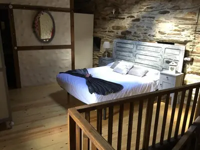 a bedroom with a large bed with a stone wall at CASA RURAL BIERZO ENCANTADO in Valle de Finolledo