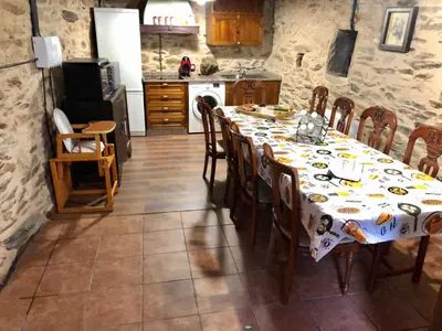 a dining room with a table and a kitchen at CASA RURAL BIERZO ENCANTADO in Valle de Finolledo