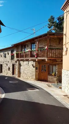 a stone house with a balcony on a street at CASA RURAL BIERZO ENCANTADO in Valle de Finolledo