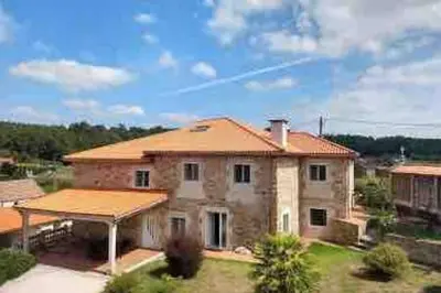 a large stone house with a roof at Casa de Fares in A Estrada
