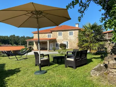 a patio with a table and chairs and an umbrella at Casa de Fares in A Estrada