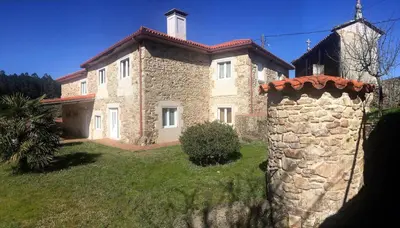 a large stone house with a stone wall at Casa de Fares in A Estrada
