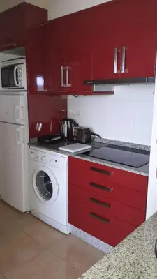 a kitchen with red cabinets and a washing machine at Panoramico Playa de Altar II in Barreiros