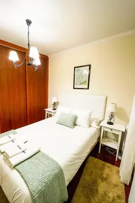 a bedroom with a large white bed and a table at Miranda VUT-PO-004637 in Caldas de Reis