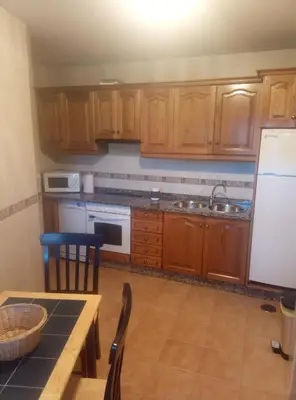 a kitchen with wooden cabinets and a table and a refrigerator at Casa Rural Leonor in San Ciprián