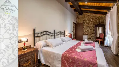 a bedroom with a large bed and a stone wall at Pensión As Hortas in Palas de Rei
