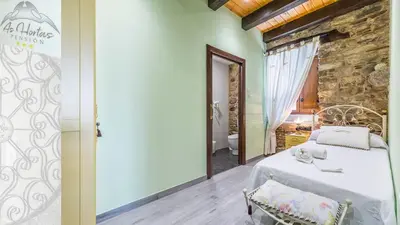 a bedroom with a white bed and a stone wall at Pensión As Hortas in Palas de Rei