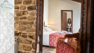 a bedroom with a bed and a stone wall at Pensión As Hortas in Palas de Rei