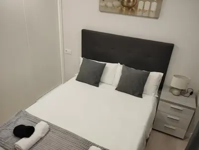 a bedroom with a white bed with a black headboard at Alojamiento Buenos Aires in Ourense