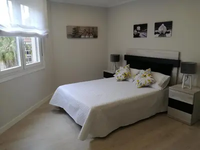 a bedroom with a white bed and two windows at Alojamiento Buenos Aires in Ourense