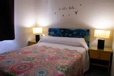 a bedroom with a bed with a colorful blanket and two lamps at Casona de Rabanal-Oca in Rabanal del Camino