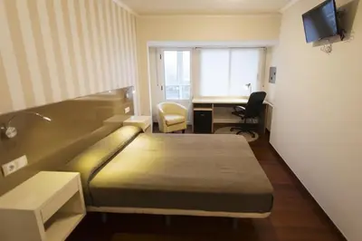 a hotel room with a bed and a desk with a computer at Residencia Compostela in Santiago de Compostela