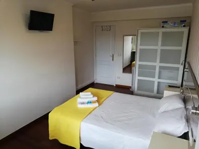 a bedroom with a white bed with a yellow blanket at Residencia Compostela in Santiago de Compostela