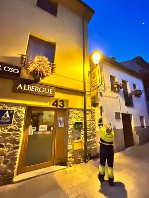 a person holding a street light on a building at SEÑOR OSO in Molinaseca