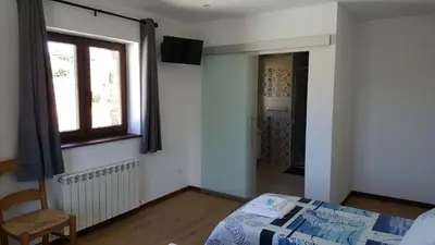 a bedroom with a bed and a window and a chair at La Posada del Druida in Foncebadón