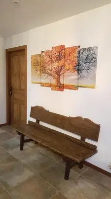 a wooden bench sitting next to a wall with paintings at La Posada del Druida in Foncebadón