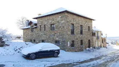 a car covered in snow in front of a building at La Posada del Druida in Foncebadón