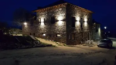 a stone building with a car parked in front of it at night at La Posada del Druida in Foncebadón