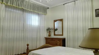 a bedroom with white curtains and a bed and a mirror at Casa Braña in Barreiros