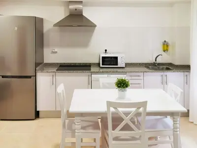 a kitchen with a white table and chairs and a refrigerator at Duerming Family Viveiro 3 Rooms in Viveiro