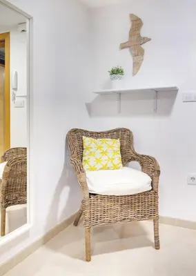 a wicker chair with a yellow pillow in a room at Duerming Family Viveiro 3 Rooms in Viveiro