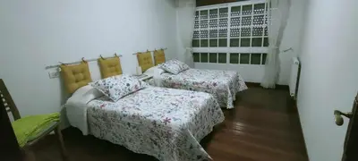 a room with two beds and a chair and a window at Apartamento de 4 habitaciones en el Centro de Monforte in Monforte de Lemos
