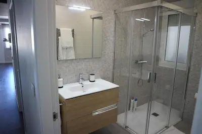 a bathroom with a sink and a glass shower at FOROPLAZA Porta San Pedro Pleno Centro Vistas Muralla in Lugo