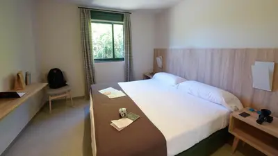 a hotel room with a large bed and a desk at Albergue Monte Do Gozo in Santiago de Compostela