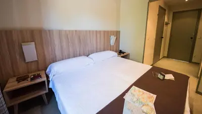 a bedroom with a large white bed and two tables at Albergue Monte Do Gozo in Santiago de Compostela