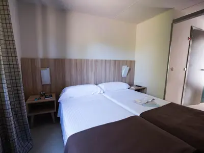 a hotel room with a large bed and a night stand at Albergue Monte Do Gozo in Santiago de Compostela