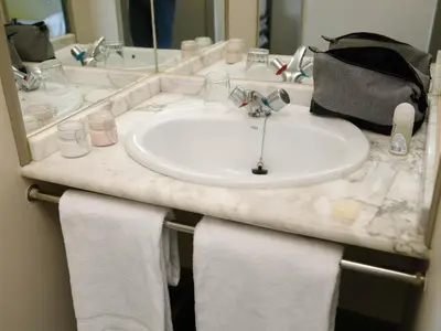 a bathroom counter with a sink and towels at Albergue Monte Do Gozo in Santiago de Compostela