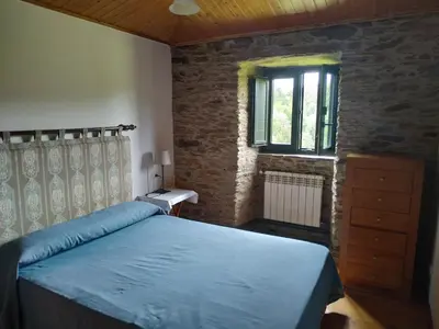 a bedroom with a blue bed and a window at Casa O Castelo en Touro in Touro