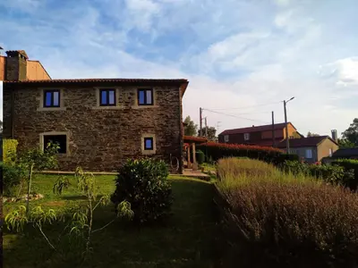 a stone house with blue windows in a yard at Casa O Castelo en Touro in Touro