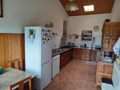 a kitchen with a white refrigerator and wooden cabinets at Casa O Castelo en Touro in Touro