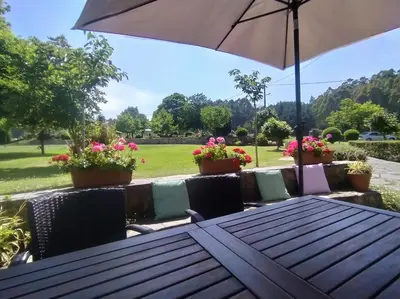 a wooden table with an umbrella and some flowers at Casa Valle in Foz