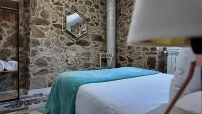 a bedroom with a bed and a stone wall at PANTON RURAL Casa Do José in Pantón