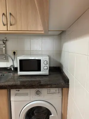 a kitchen with a microwave and a washing machine at PR Campanas de San Juan in Santiago de Compostela