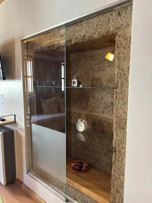 a glass shower in a bathroom with a stone wall at PR Campanas de San Juan in Santiago de Compostela