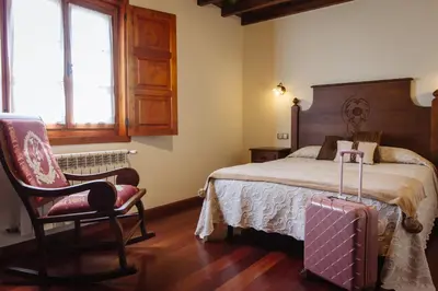 a bedroom with a bed and a chair with a suitcase at Apartamentos Porcia in Tapia de Casariego