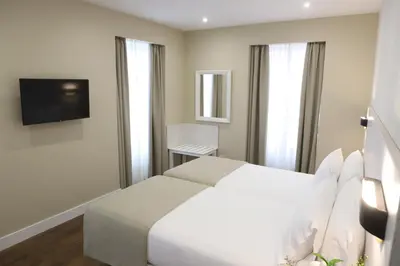 a bedroom with a white bed and a television at VÍA XIX in Caldas de Reis