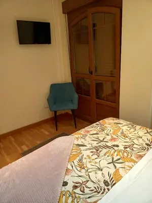 a bedroom with a bed and a blue chair at EDIFICIO CINE MON in Burela de Cabo