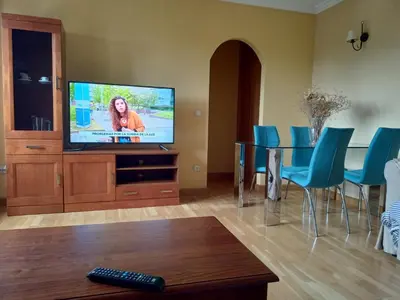 a living room with a television and blue chairs at EDIFICIO CINE MON in Burela de Cabo