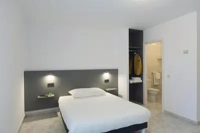 a bedroom with a white bed and a bathroom at Pensión Dorotea in Lavacolla