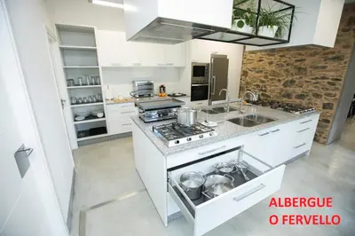 a white kitchen with a stove and a sink at Pensión Dorotea in Lavacolla