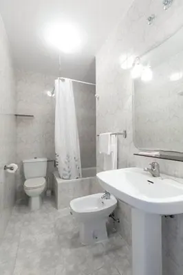 a white bathroom with a sink and a toilet at Pensión Dorotea in Lavacolla