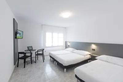 a hotel room with two beds and a table and a desk at Pensión Dorotea in Lavacolla