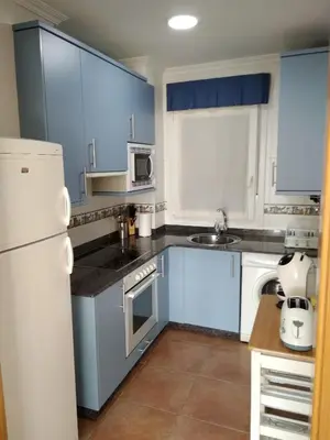 a kitchen with blue cabinets and a white refrigerator at Ribadeo Centro in Ribadeo