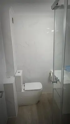 a white bathroom with a toilet and a glass shower at La mesa del cocinero in Lugo